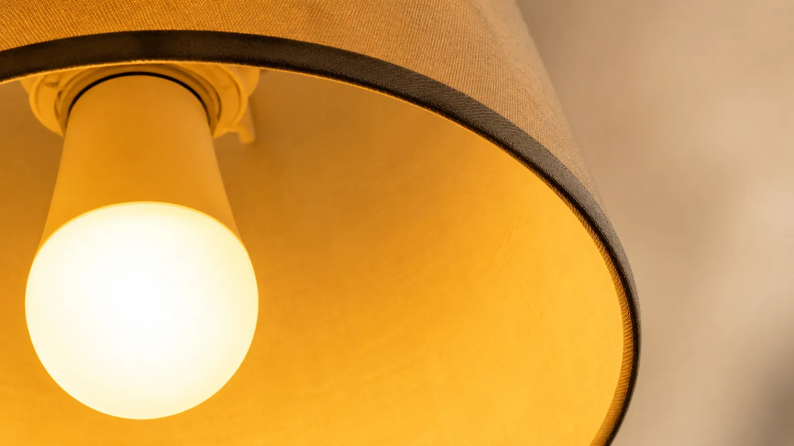 Warm 2700K lamplight reading golden against cream plaster and oak.
