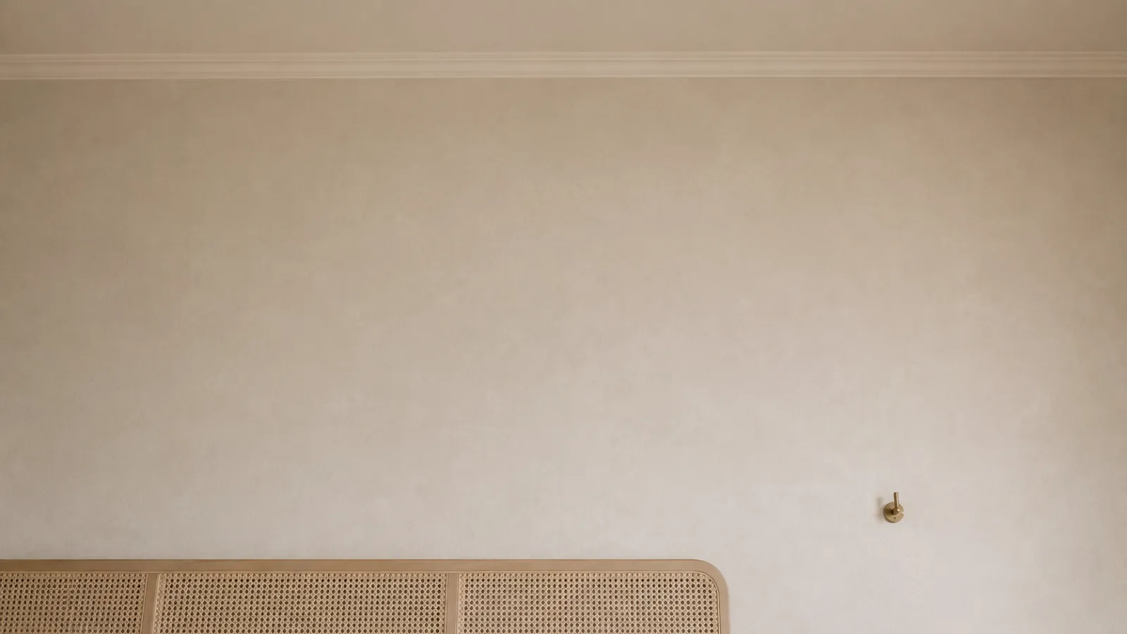 Bare upper wall left empty above a caned bench, showing how negative space adds air to a room.